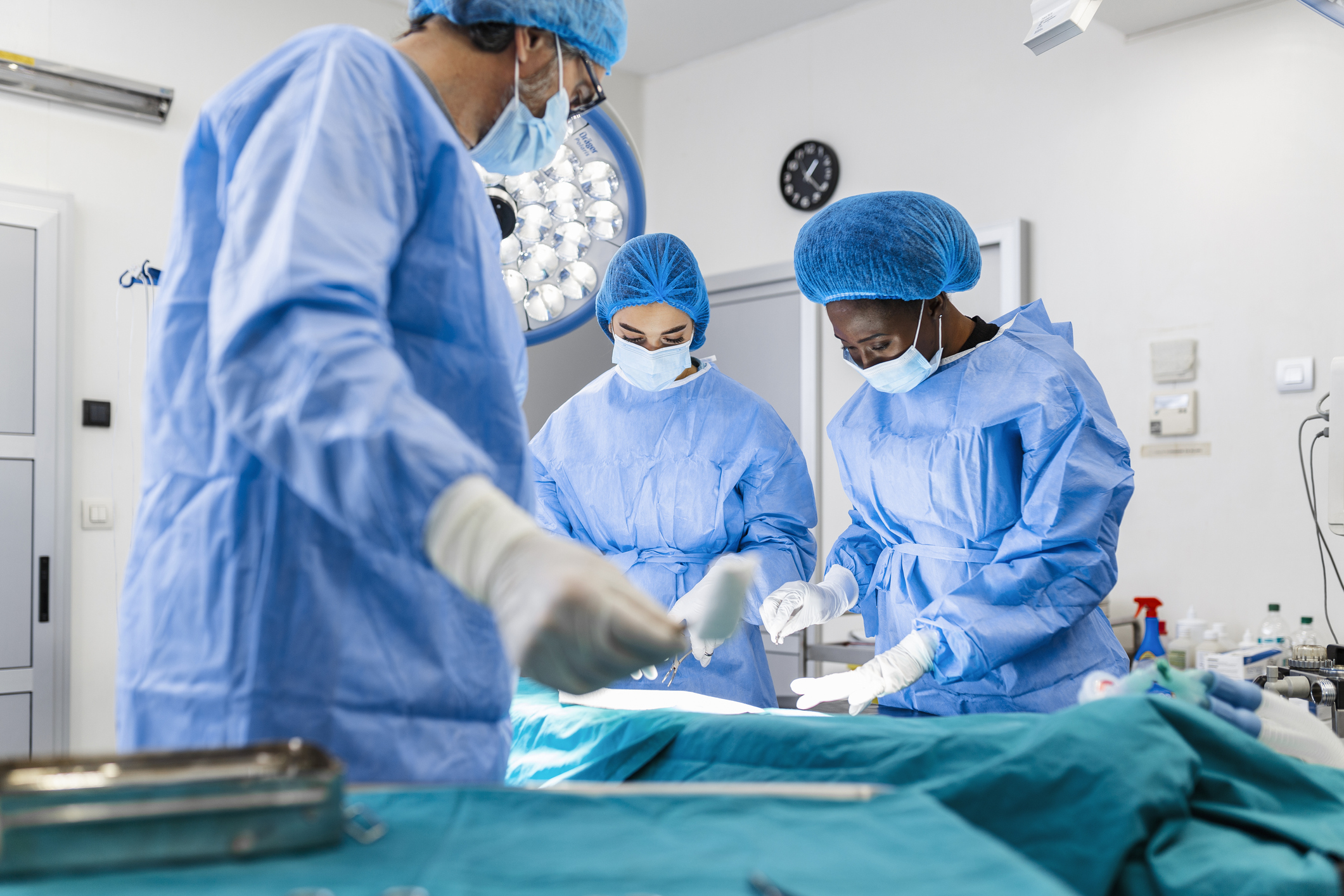 Operating Room of Surgical Table with Instruments, Assistant Picks up Instruments for Surgeons During Operation. Surgery in Progress. Professional Medical Doctors Performing Surgery