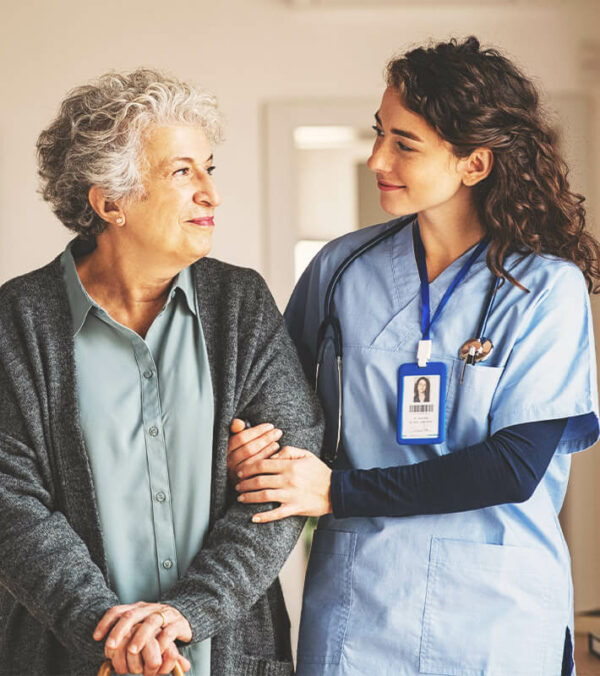 Young caregiver helping senior woman walking. Nurse assisting her old woman patient at nursing home. Senior woman with walking stick being helped by nurse at home.