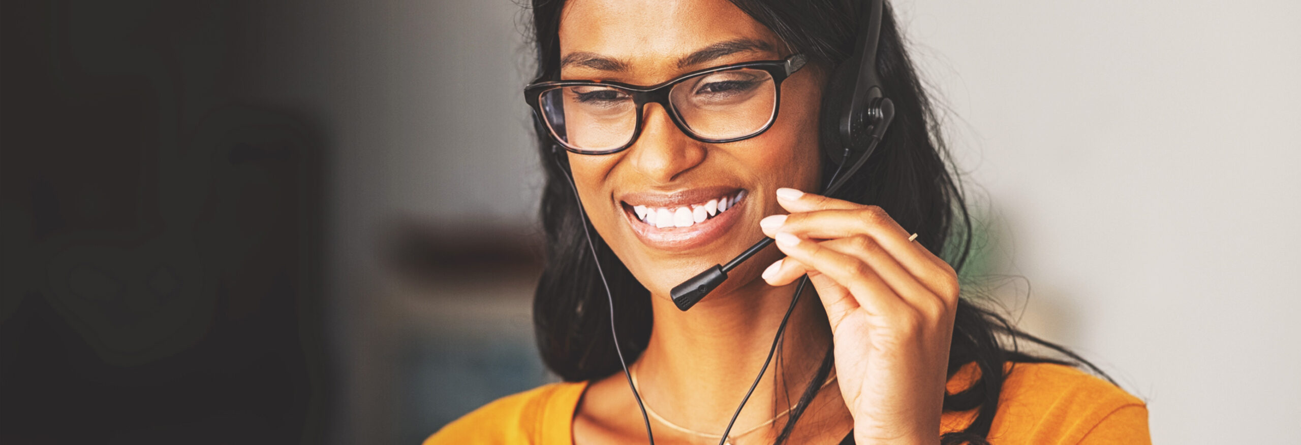IT specialist female worker, wearing a headset smiling while giving advice at over the phone