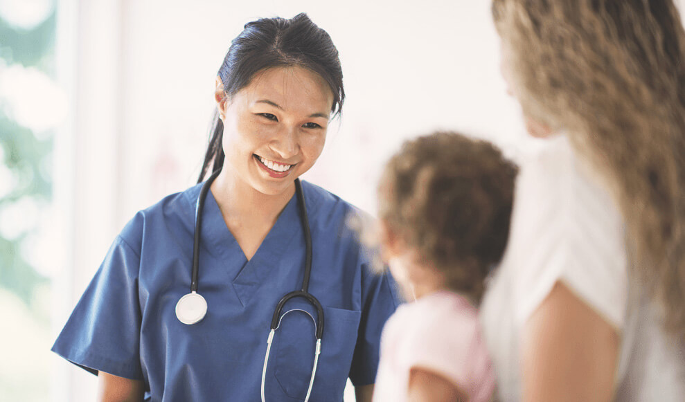 A little girl is at the doctors office for a check up. A nurse is sitting with them and talking to the mother.