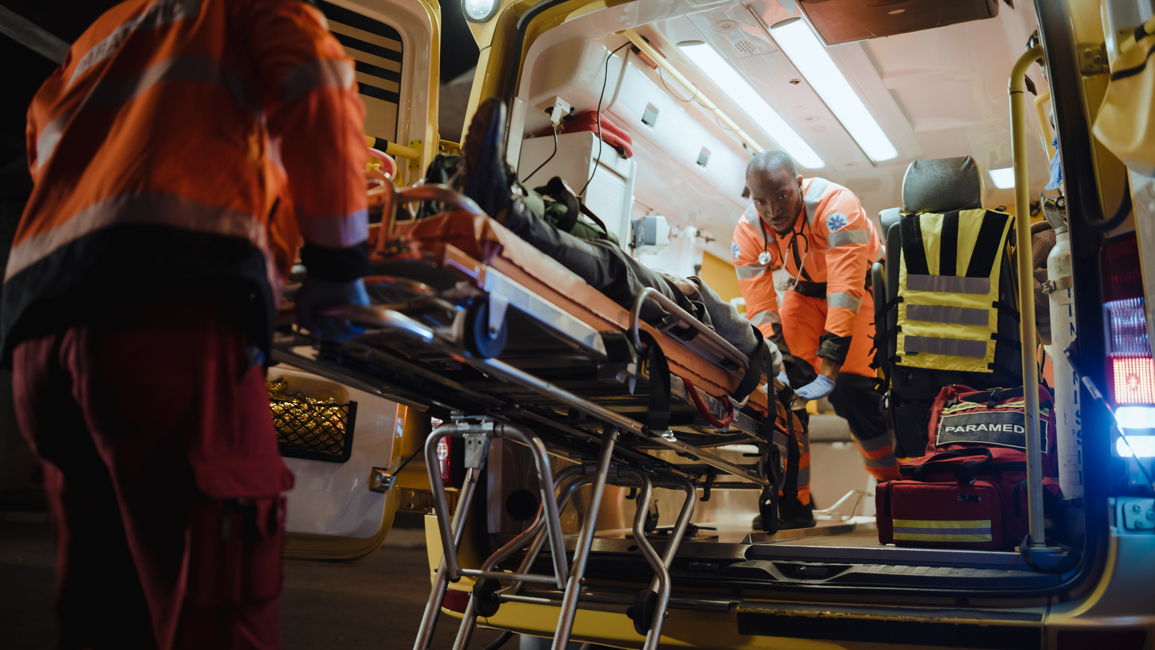 Team of EMS Paramedics React Quick to Bring Injured Patient to Healthcare Hospital and Get Him Out of Ambulance on a Stretcher. Emergency Care Assistants Help Young Man to Stay Alive After Accident.