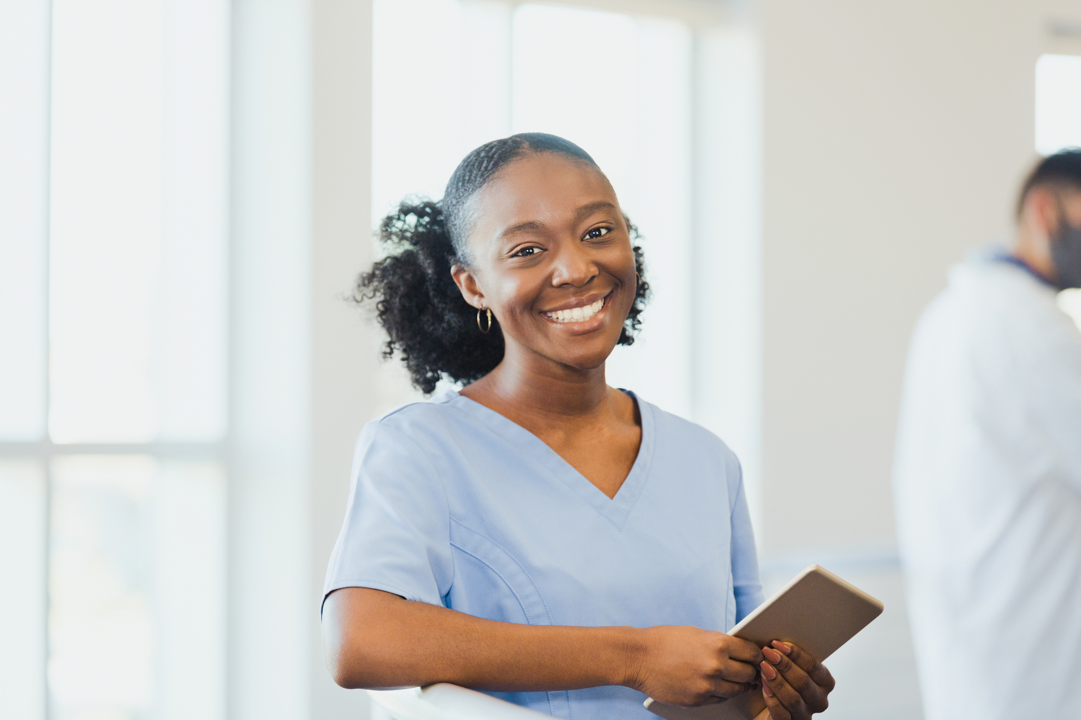 A smiling young female nurse looks at the camera while working in a hospital.