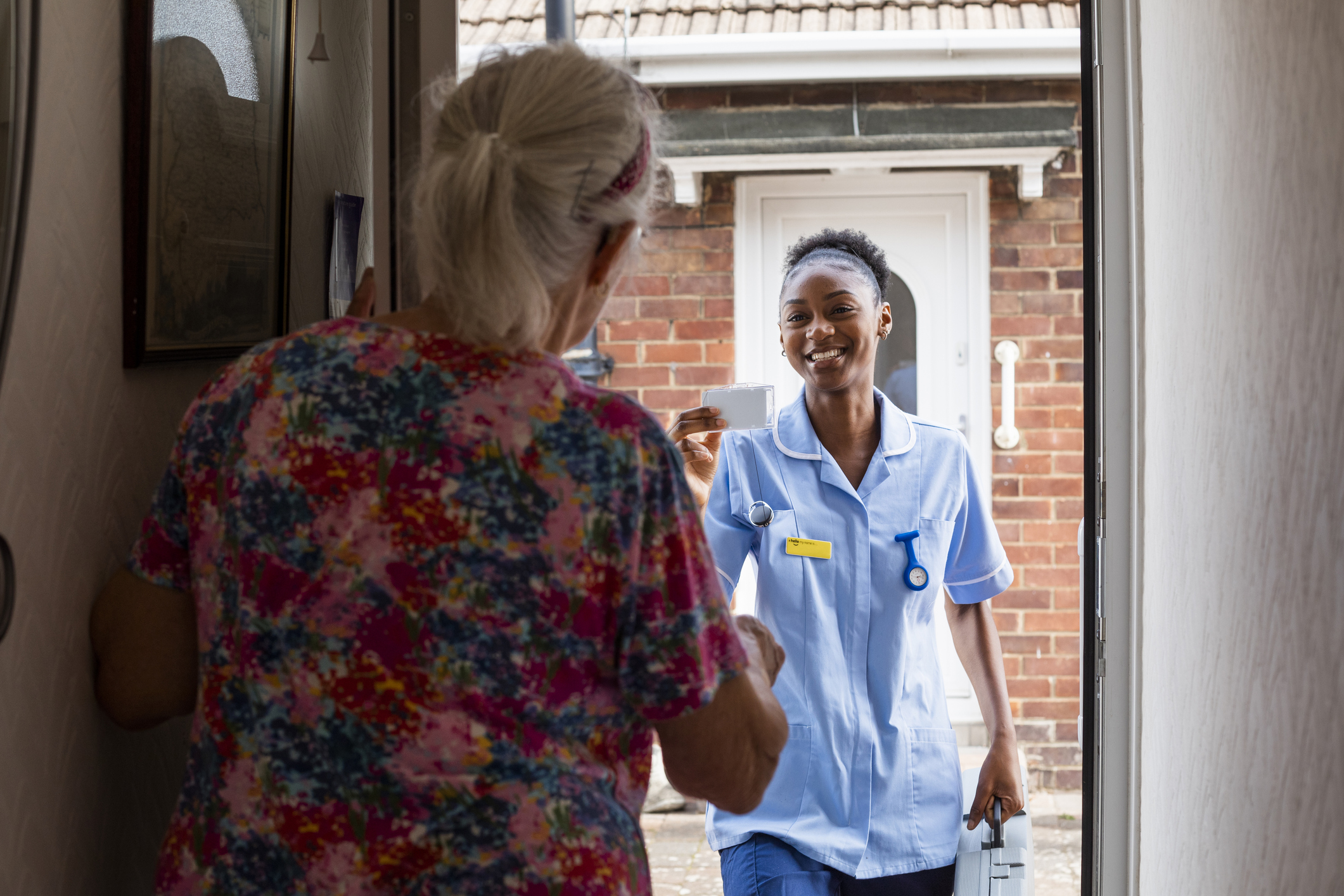 Nurse arriving at a patient's house showing her ID card in the North East of England. She is a home caregiver.