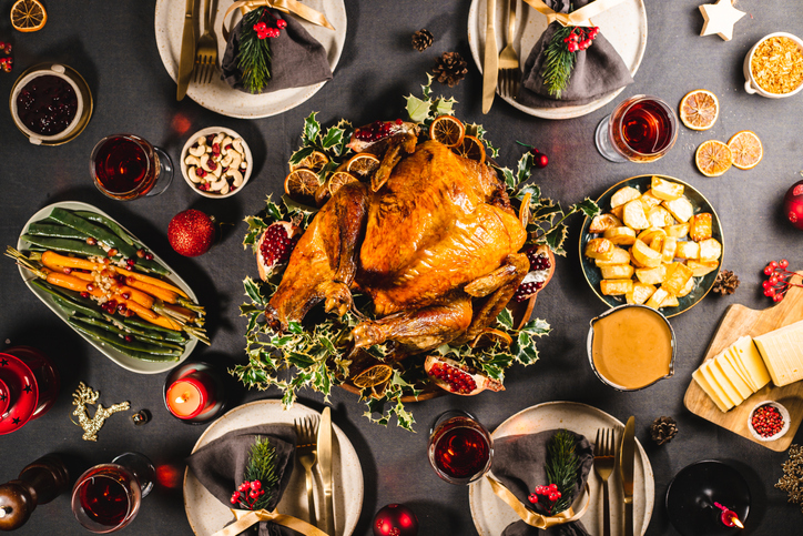 Top down view of a delicious Christmas meal with roasted Turkey, carrots, cashews, pomegranates, dried oranges and red wine on the dinner table.