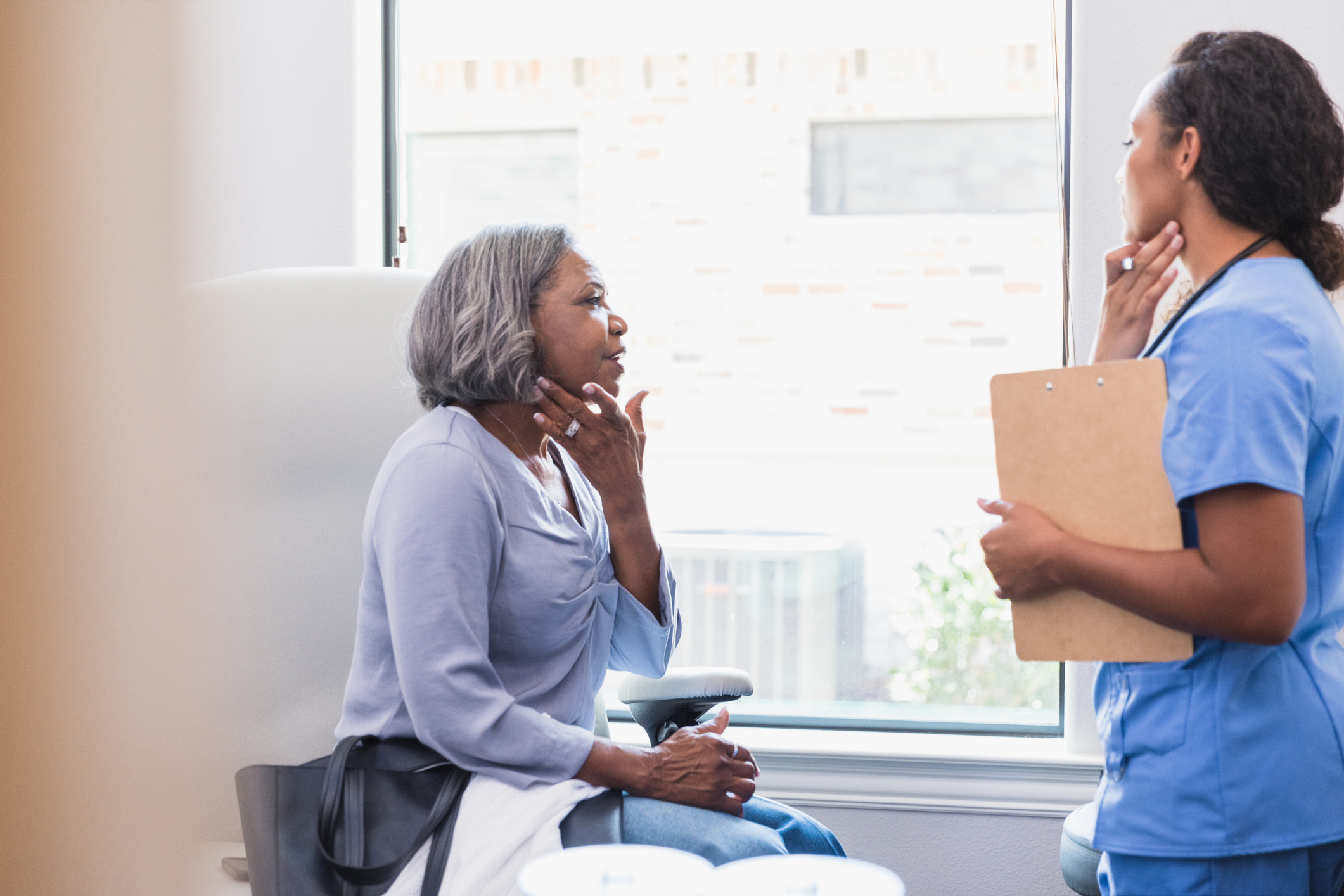 patient conversing with healthcare professional holding files