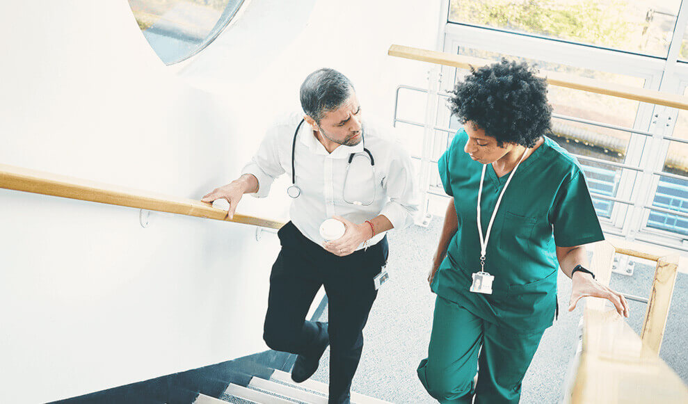 Healthcare professionals in uniform walking up stairs in hospital