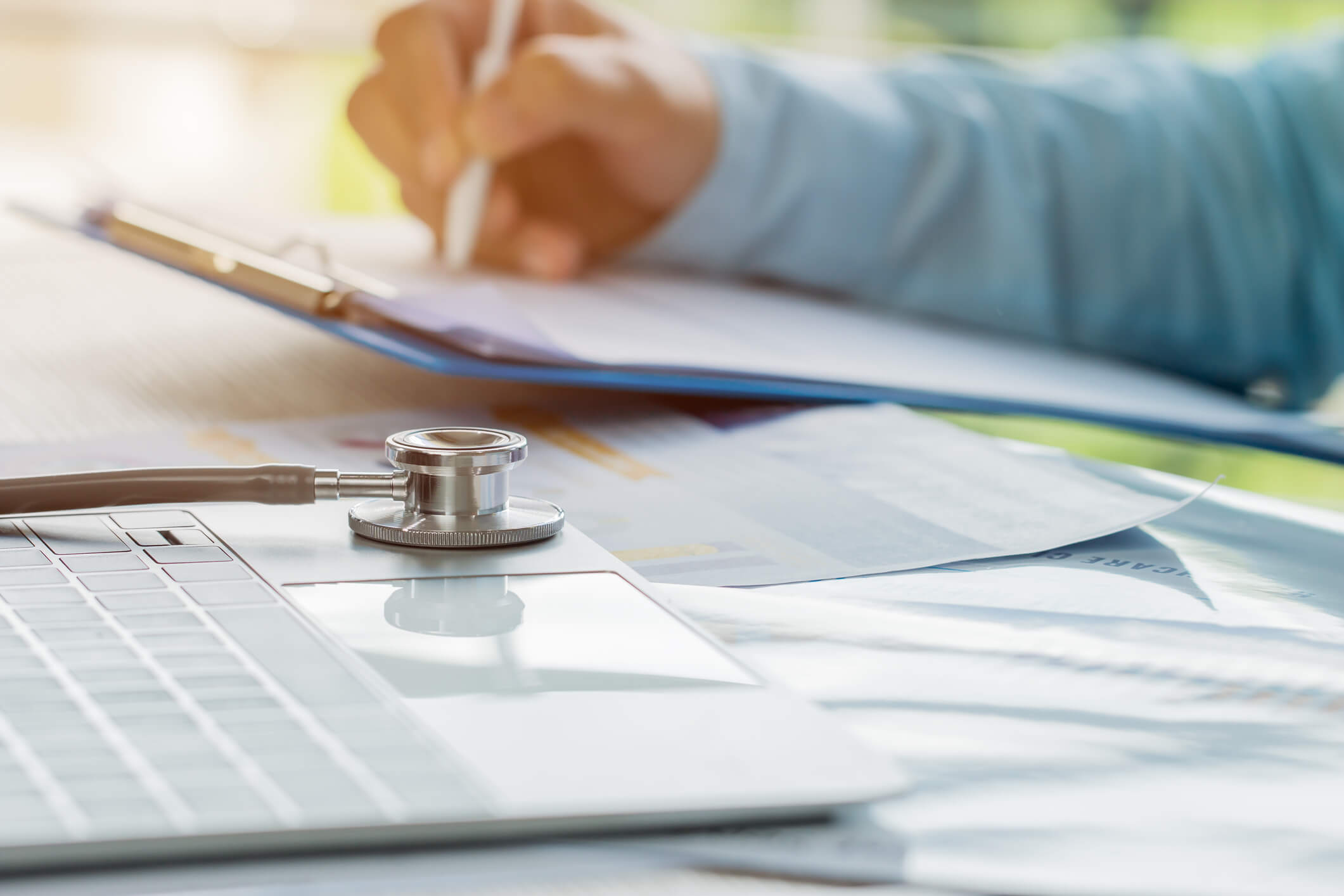 Doctor working in hospital writing prescription clipboard, working an Laptop on desk in hospital with report analysis, Healthcare and medical concept, selective focus