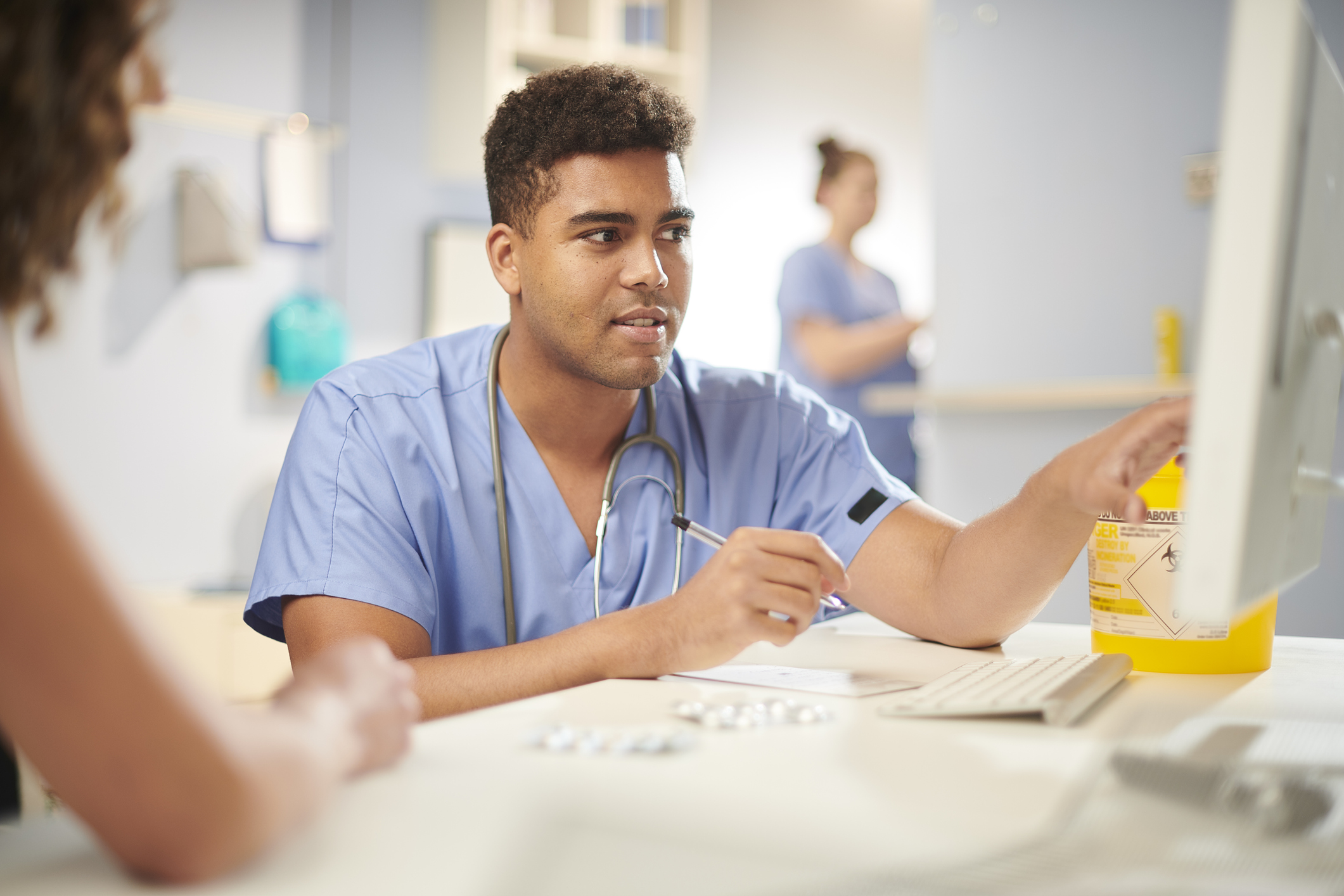 Male doctor discussing medical records with patient, pointing at a computer screen