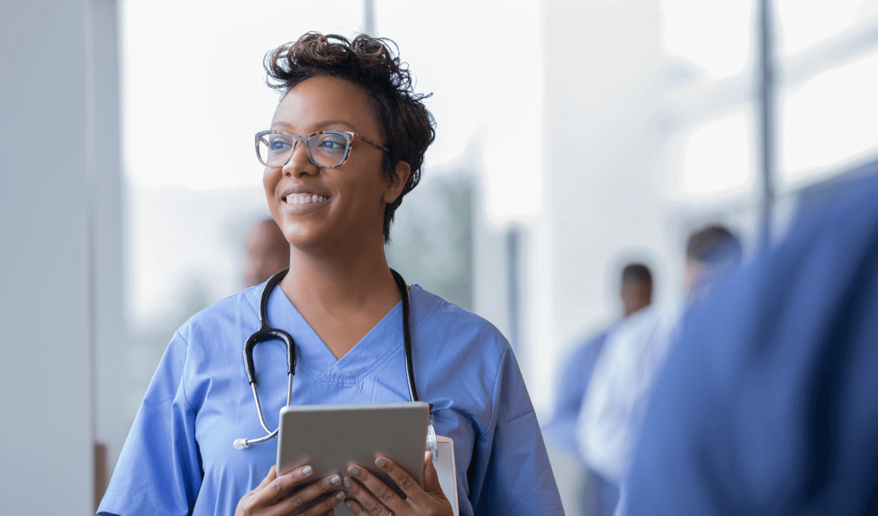 Cheerful Doctor walking through hospital holding a digital tablet