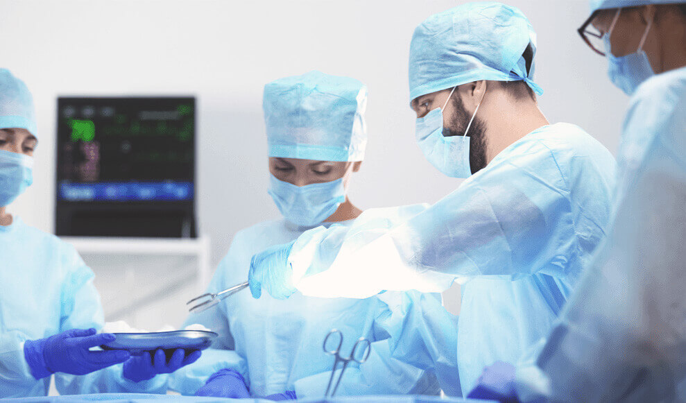 Male doctor operating holding tongs during an operation surrounded by colleagues