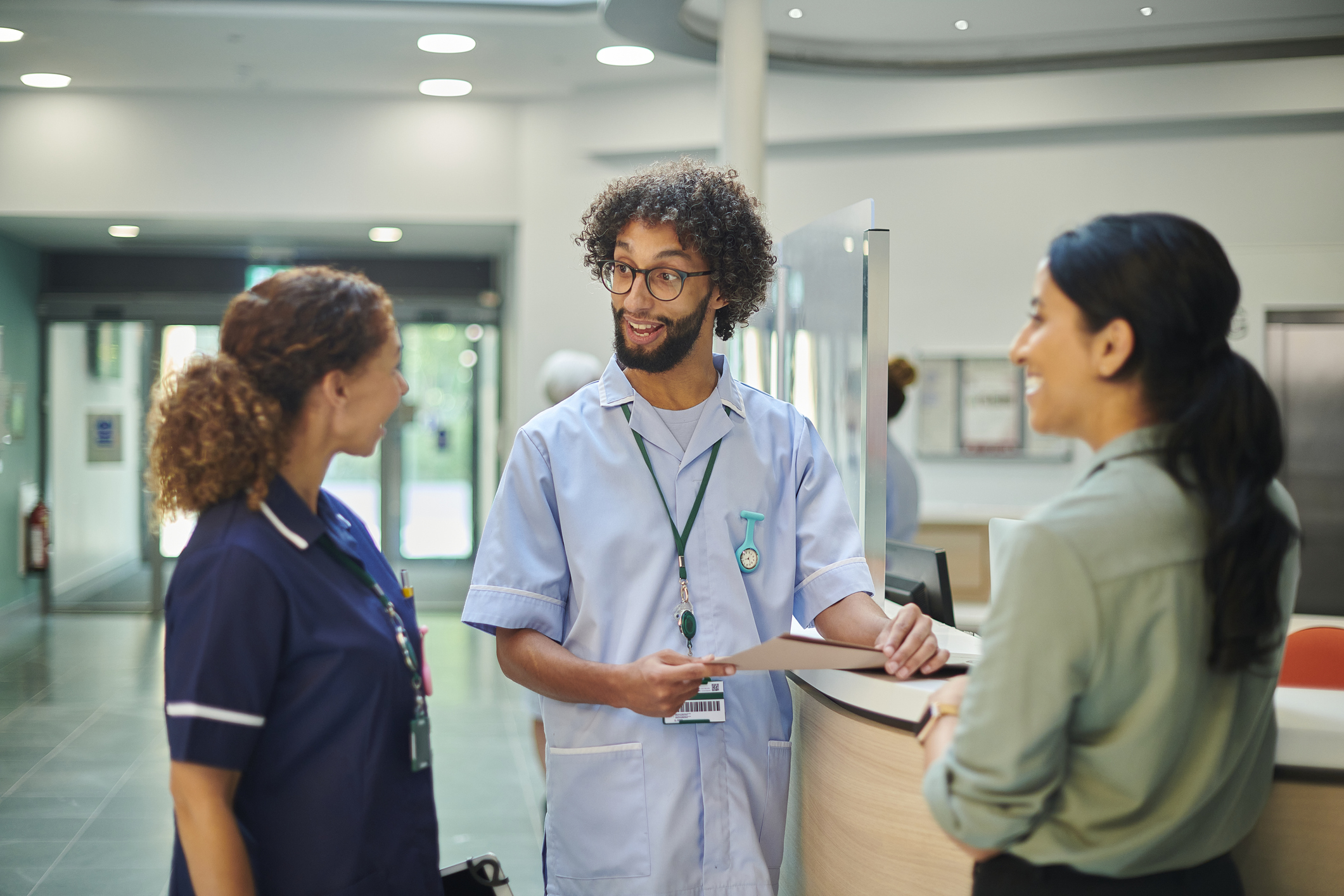 Group of medical professionals having a casual chat around a desk in a hospital lobby