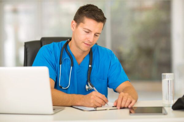 Professional male nurse writing medical reports at his desk