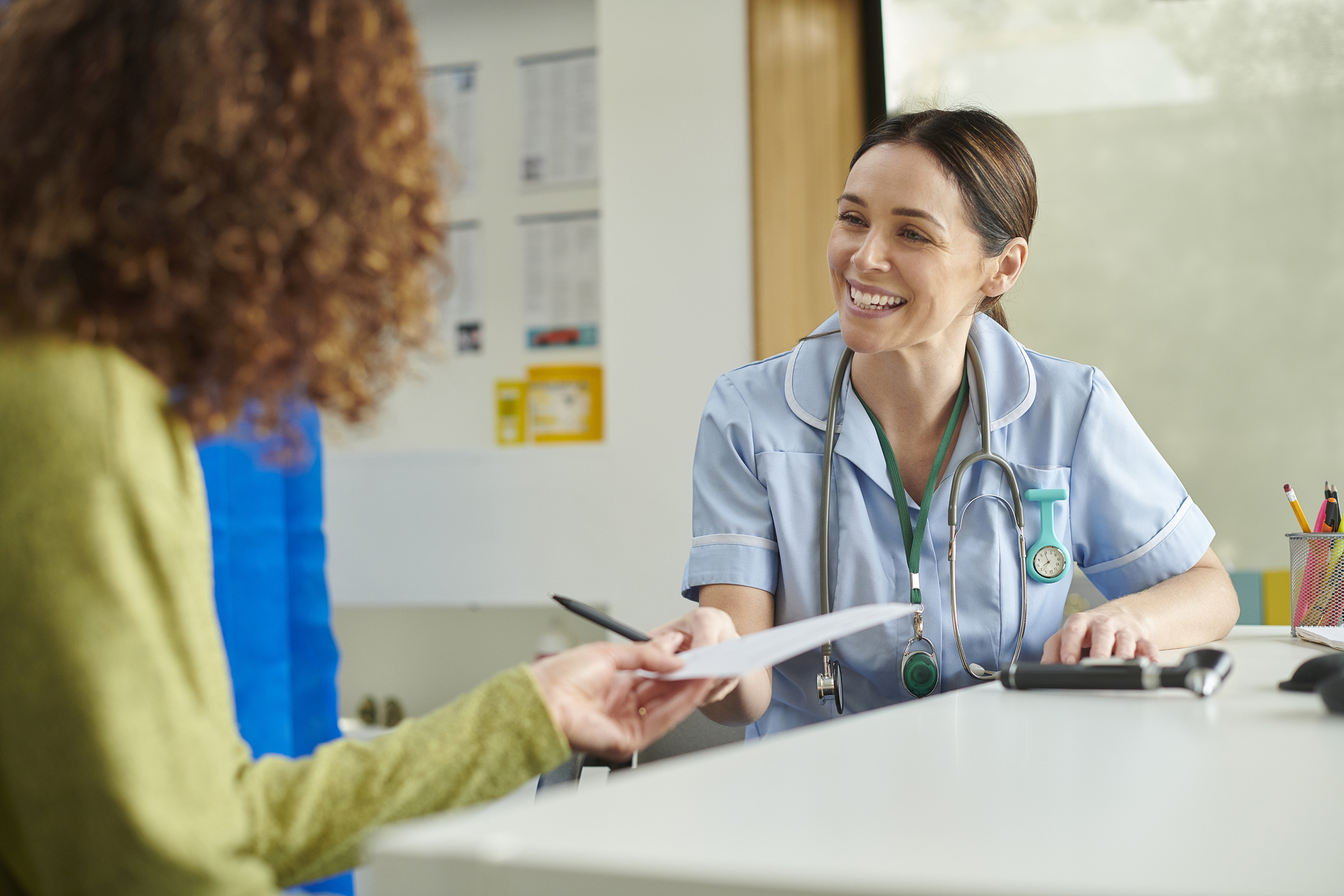 Female Nurse with female patient handing over paperwork