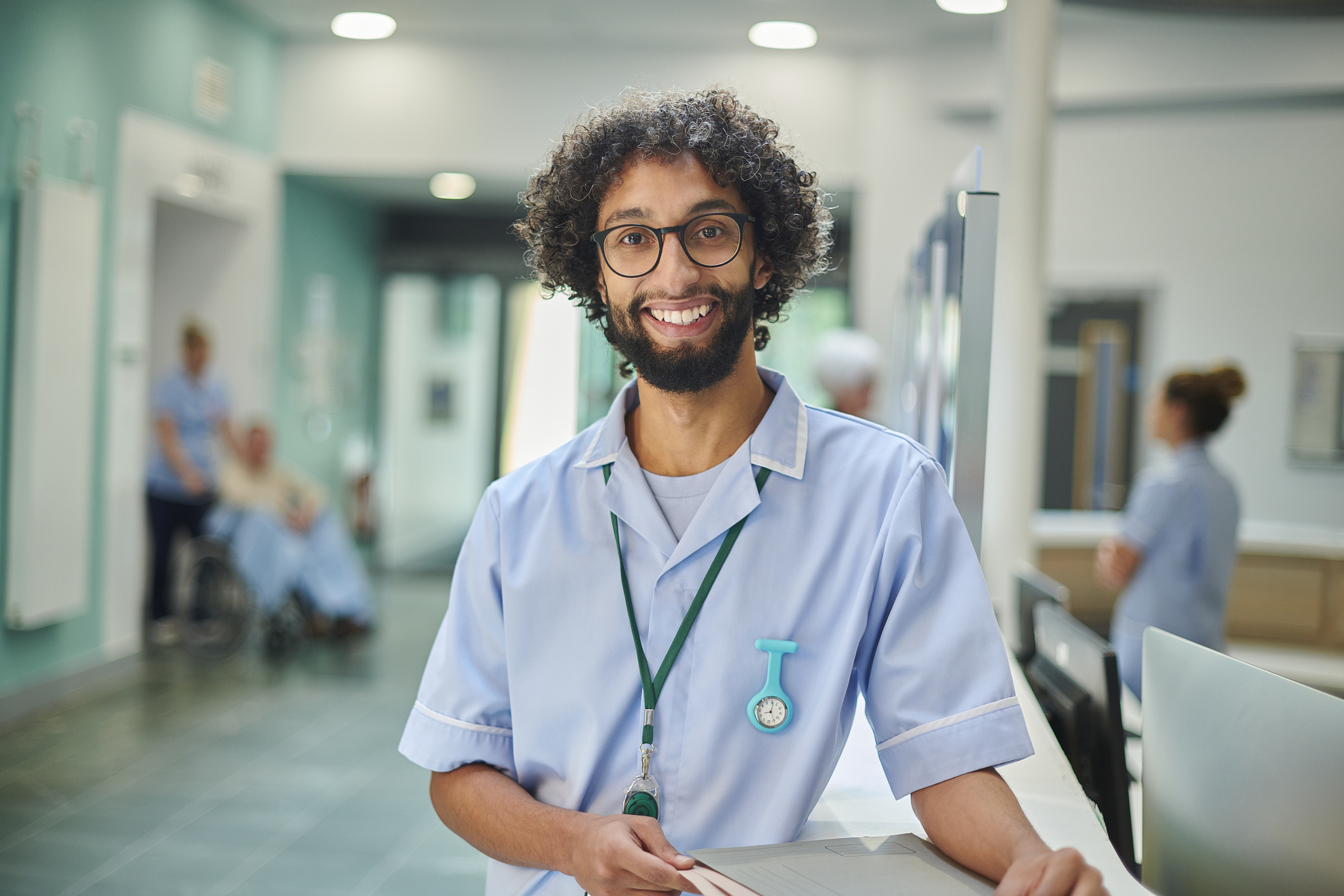 smiling male nurse in hospital foyer with patient chart
