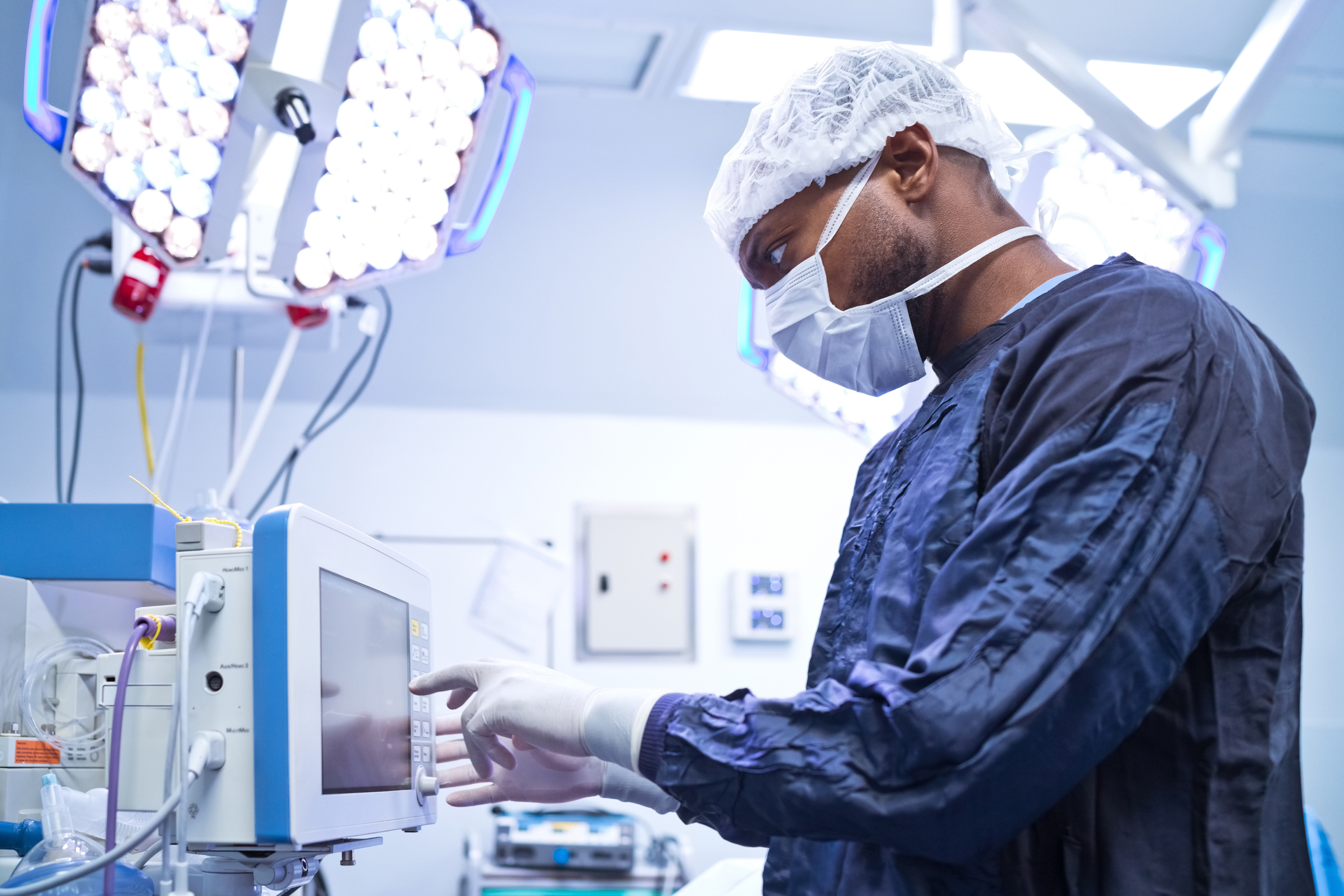 Side view of male surgeon using monitoring equipment in operating room