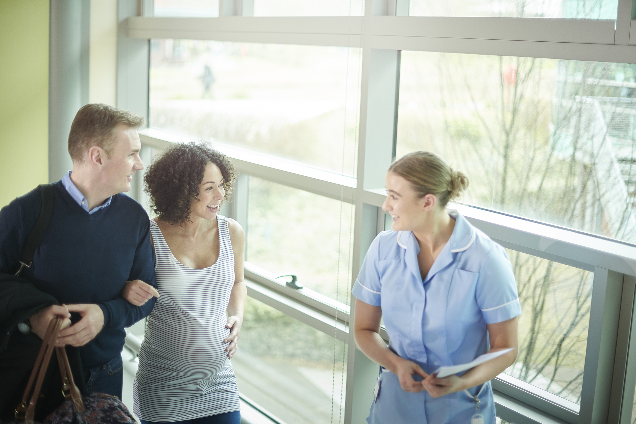 a pregnant lady arrives at the clinic greeted by a young midwife