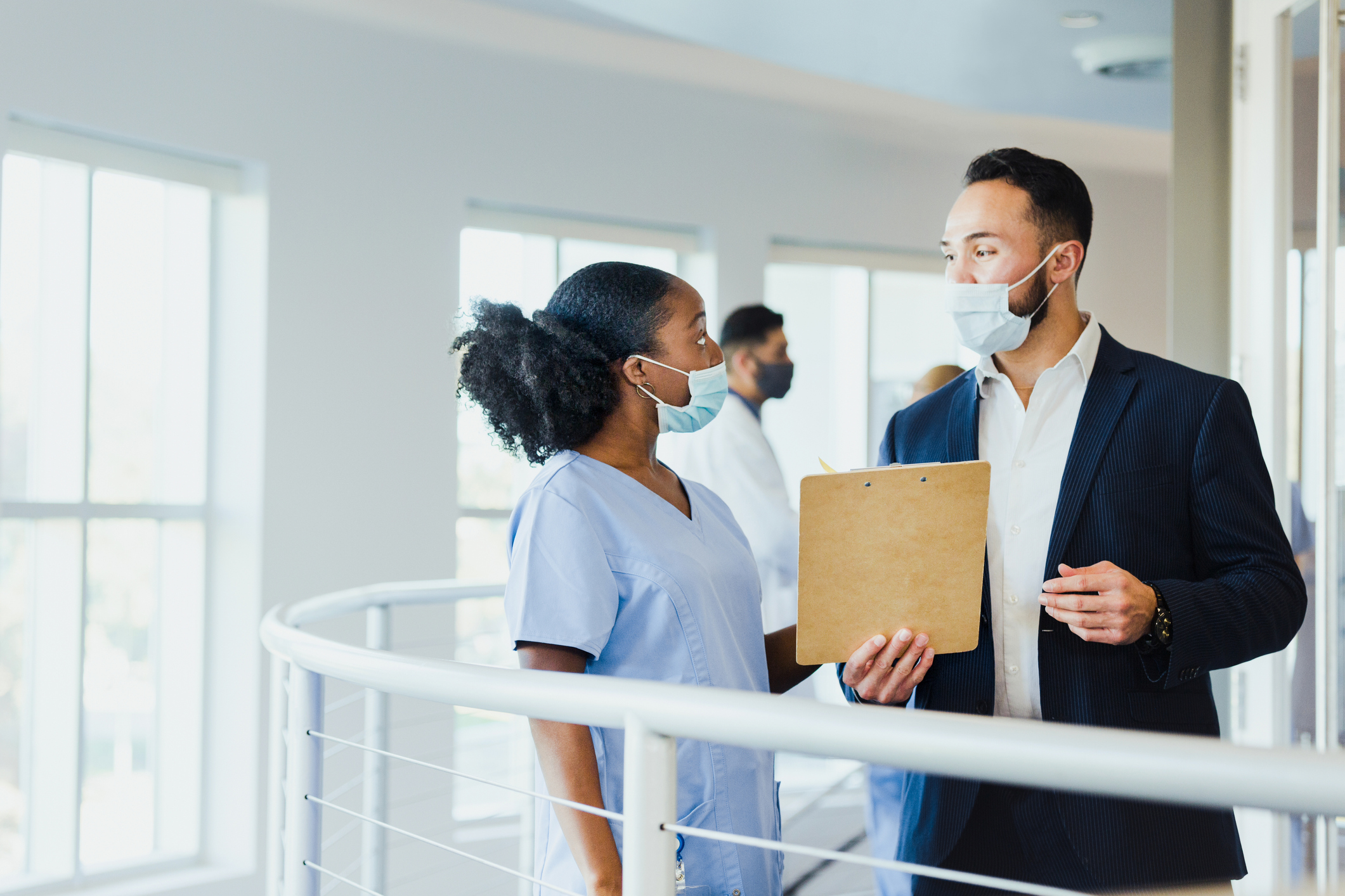 A mid adult male hospital administrator talks with female healthcare professional as they work together in a hospital.