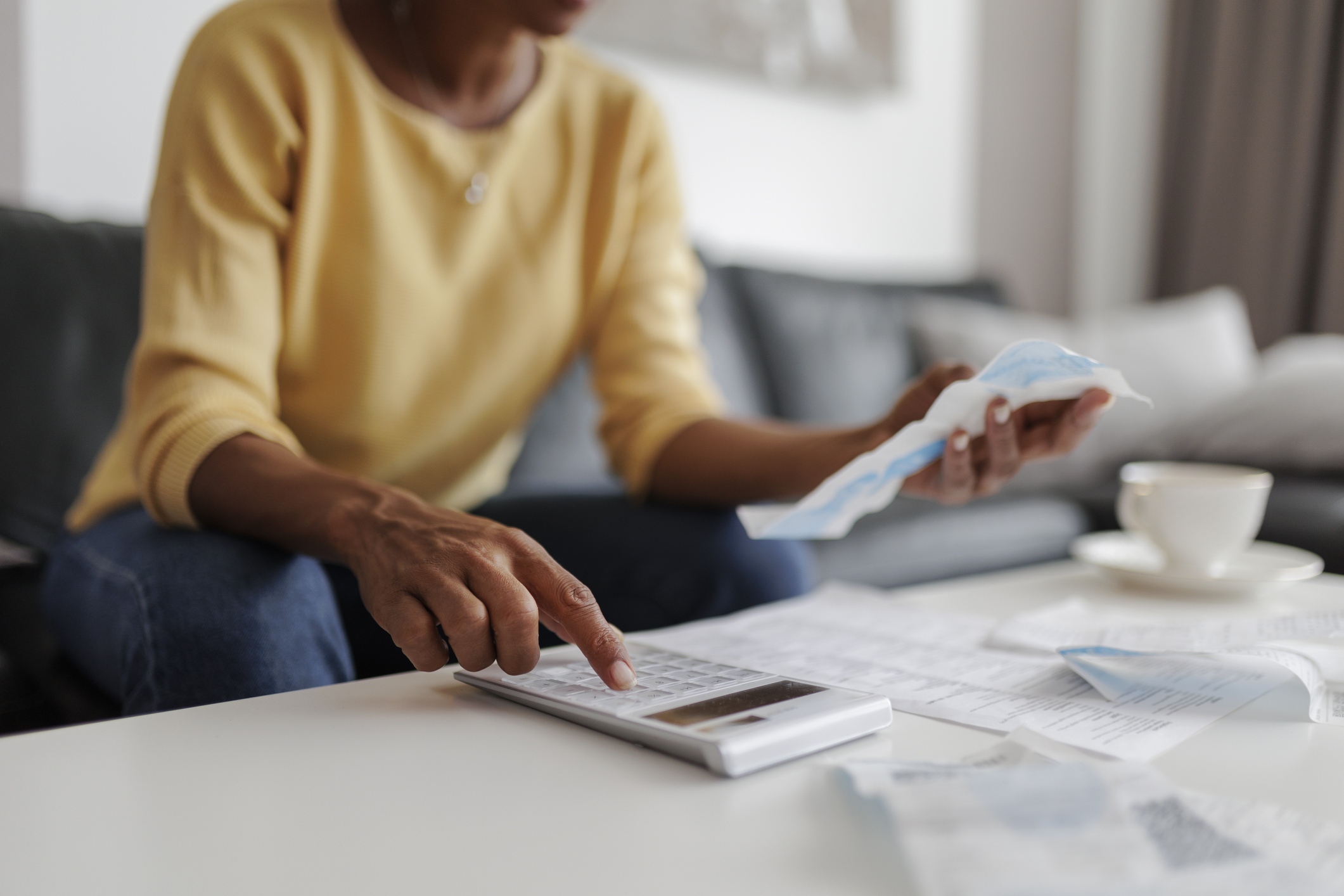 Close up of a mid adult woman checking her energy bills at home, sitting in her living room.