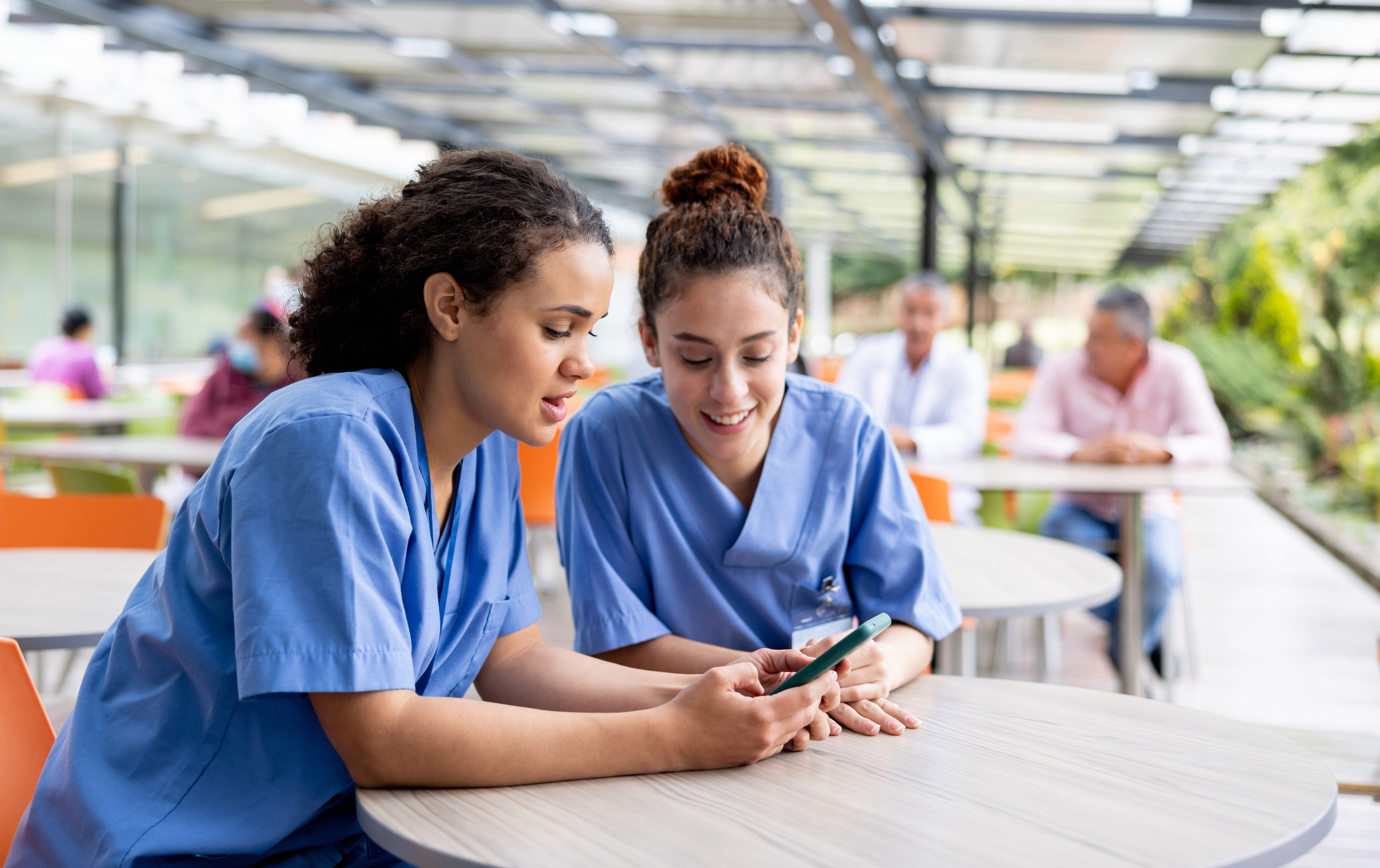 Nurses taking a break from work at the hospital and looking at social media on a cell phone at the cafeteria