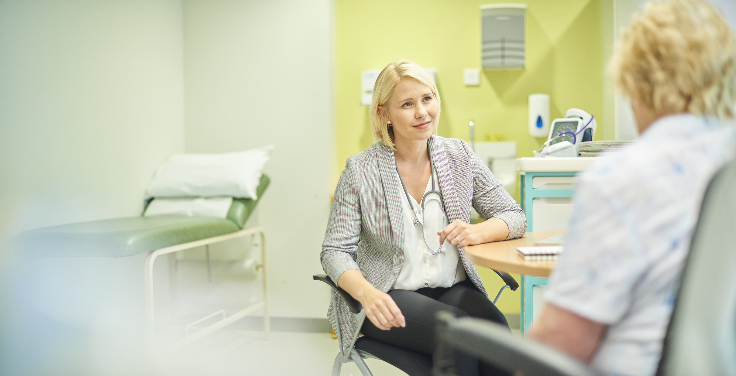 a female doctor talks to a senior patient in the clinic and writes out a prescription