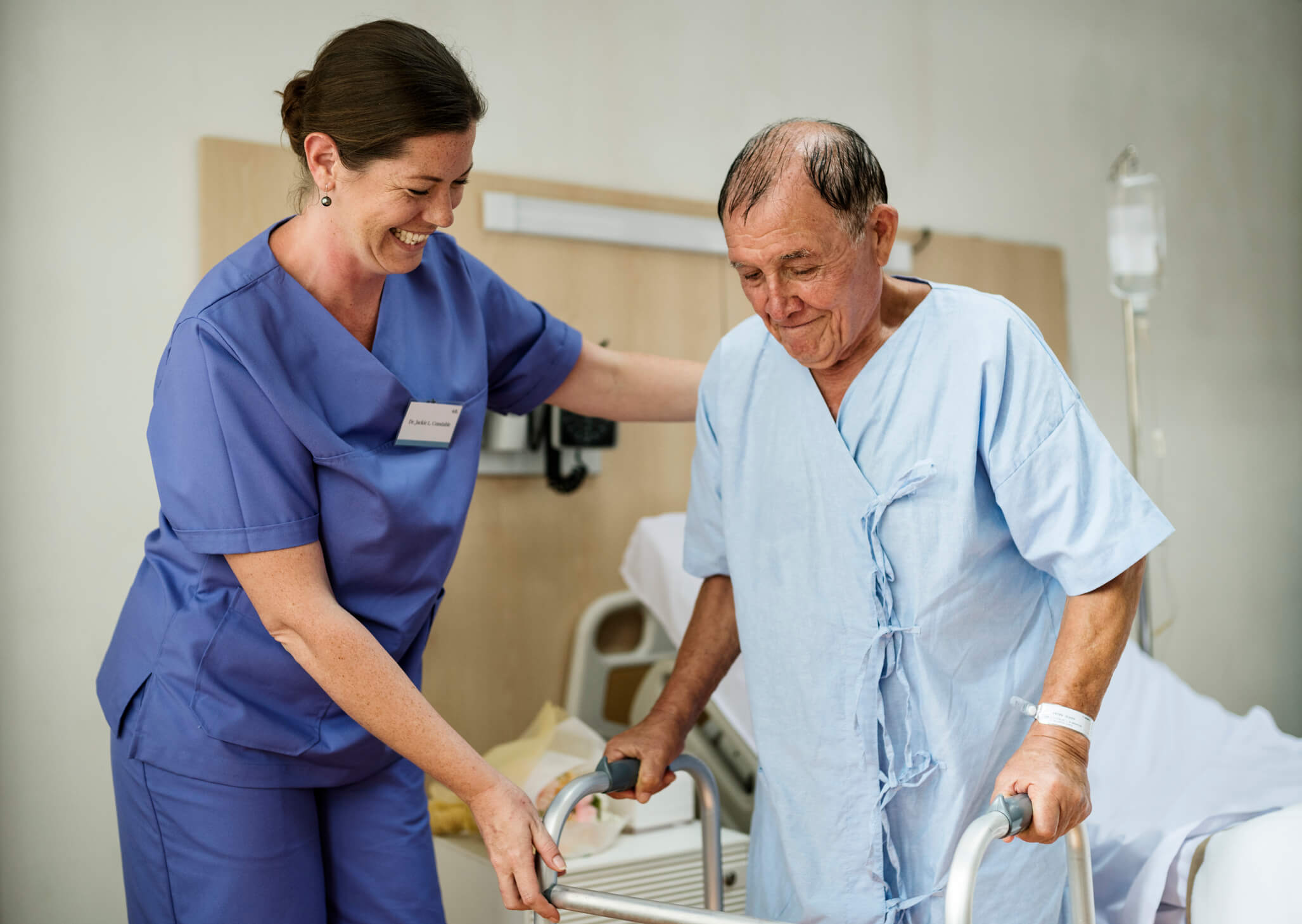 A sick elderly patient staying at a hospital being helped up by a nurse