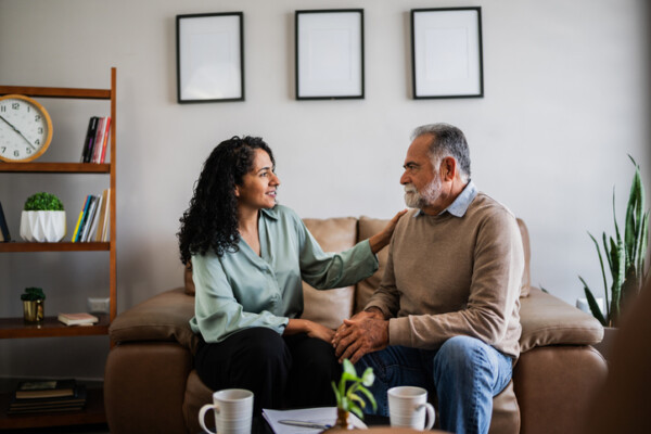Senior man being comforted by pshychotherapist during therapy session at clinic